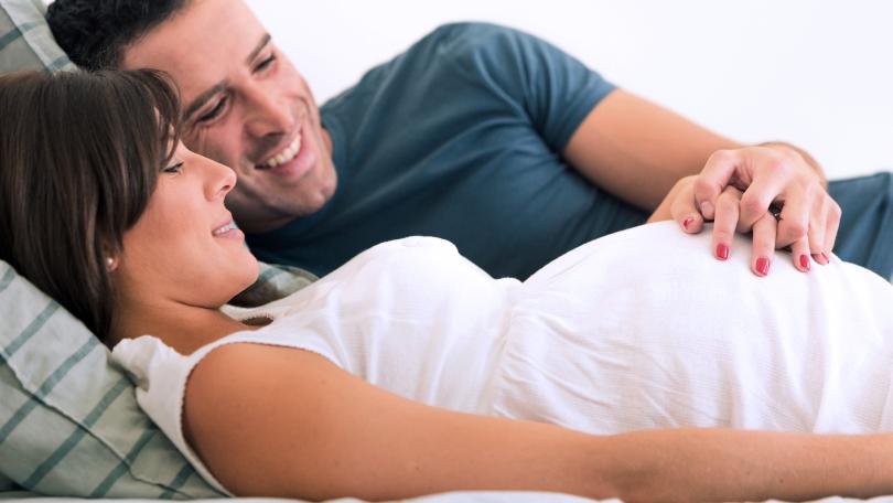 Mann hält Hand auf den Bauch einer schwangeren Frau