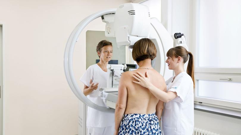 Ärztin und Krankenschwester begleiten Patientin bei Mammografie