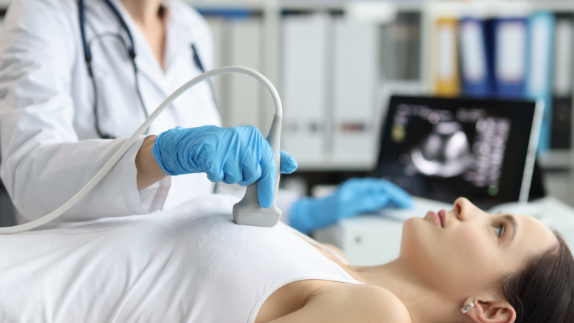 Gynäkologin untersucht die Brust einer Patientin mit einem Ultraschallgerät
